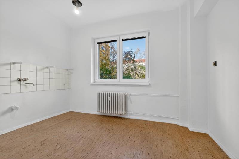 I PREDAJ Priestranný 3-izb. byt v centre Krížna/Blumentálska - Prázdna miestnosť s radiátorom a podlahou s dreveným dekorom v 3-izbovom byte.