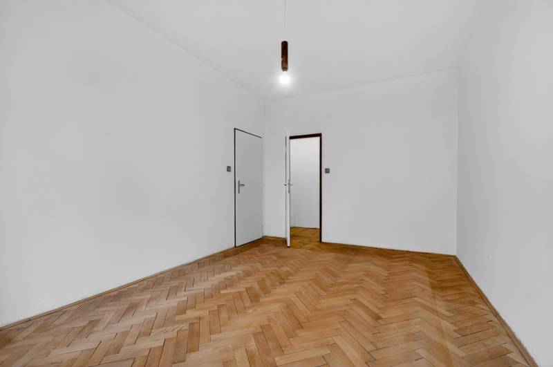 I PREDAJ Priestranný 3-izb. byt v centre Krížna/Blumentálska - Izba v 3-izbovom byte s bielymi stenami a podlahou s dreveným dekorom.