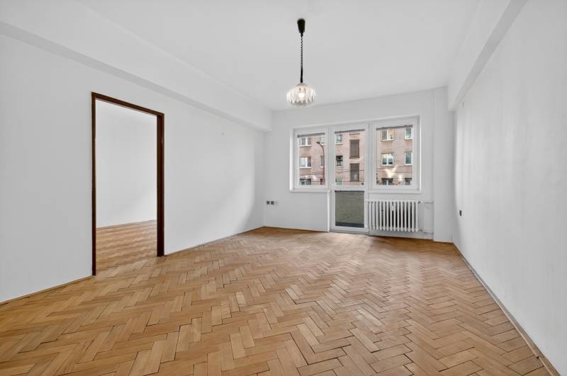 I PREDAJ Priestranný 3-izb. byt v centre Krížna/Blumentálska - Priestranná izba v 3-izbovom byte s podlahou s dreveným dekorom a balkónom.