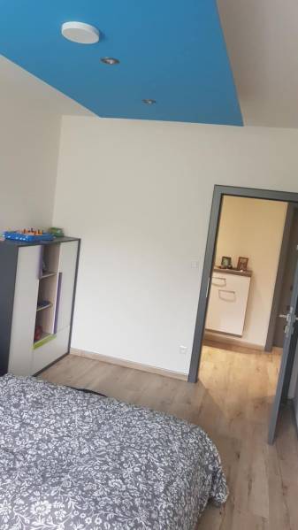 Predaj 4-izbového rodinného domu s veľkou záhradou v Semerove - Izba v rodinnom dome s podlahou s dreveným dekorom a modrým stropom.