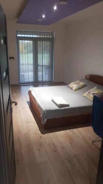 Predaj 4-izbového rodinného domu s veľkou záhradou v Semerove - Spálňa v rodinnom dome s posteľou a podlahou s dreveným dekorom.