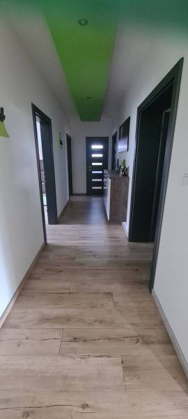 Predaj 4-izbového rodinného domu s veľkou záhradou v Semerove - Chodba v rodinnom dome s podlahou s dreveným dekorom a zelenými detailmi na strope.