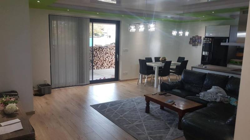 Predaj 4-izbového rodinného domu s veľkou záhradou v Semerove - Obývačka v rodinnom dome s podlahou s dreveným dekorom, pohovkou a jedálenským stolom.