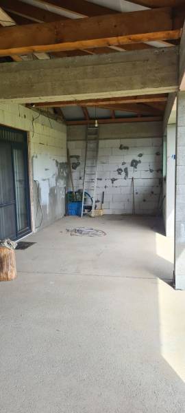 Predaj 4-izbového rodinného domu s veľkou záhradou v Semerove - Interiér rodinného domu s nevkusnými stenami, rebríkom a stavebným materiálom.