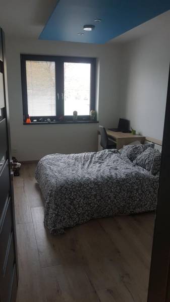 Predaj 4-izbového rodinného domu s veľkou záhradou v Semerove - Spálňa v rodinnom dome s posteľou, pracovným stolom a podlahou s dreveným dekorom.