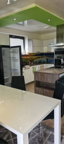 Predaj 4-izbového rodinného domu s veľkou záhradou v Semerove - Kuchyňa v rodinnom dome s otvorenou chladničkou, zeleným stropom a jedálenským stolom.
