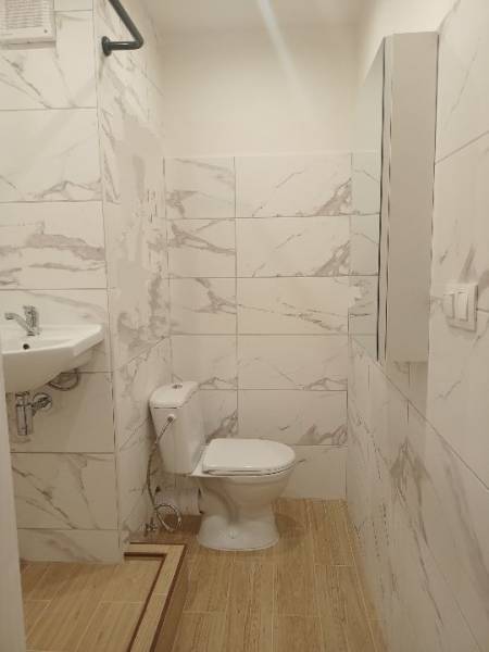 Prenájom veľmi peknej garzónky na Nábrežnej ulici - Kúpeľňa garsónky s toaletou, umývadlom a podlahou s dreveným dekorom.