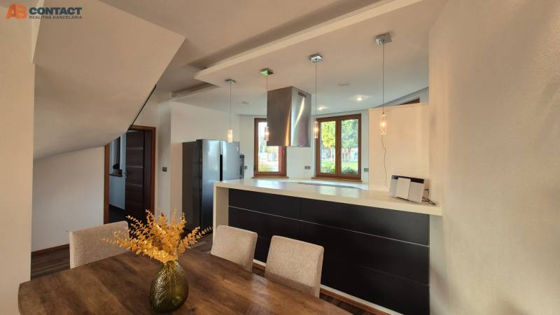 Reprezentatívny 5-izbový rodinný dom pri Piešťanoch - Kuchyňa s jedálenským stolom a podlahou s dreveným dekorom v rodinnom dome.