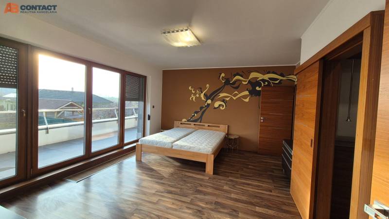 Reprezentatívny 5-izbový rodinný dom pri Piešťanoch - Miestnosť v rodinnom dome s podlahou s dreveným dekorom, dvojlôžkovou posteľou a terasou.