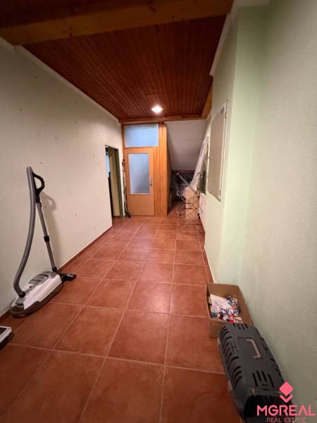 Veľký rodinný dom Podhradie  - Chodba v rodinnom dome s dlažbou, dreveným stropom a odkladacím priestorom.