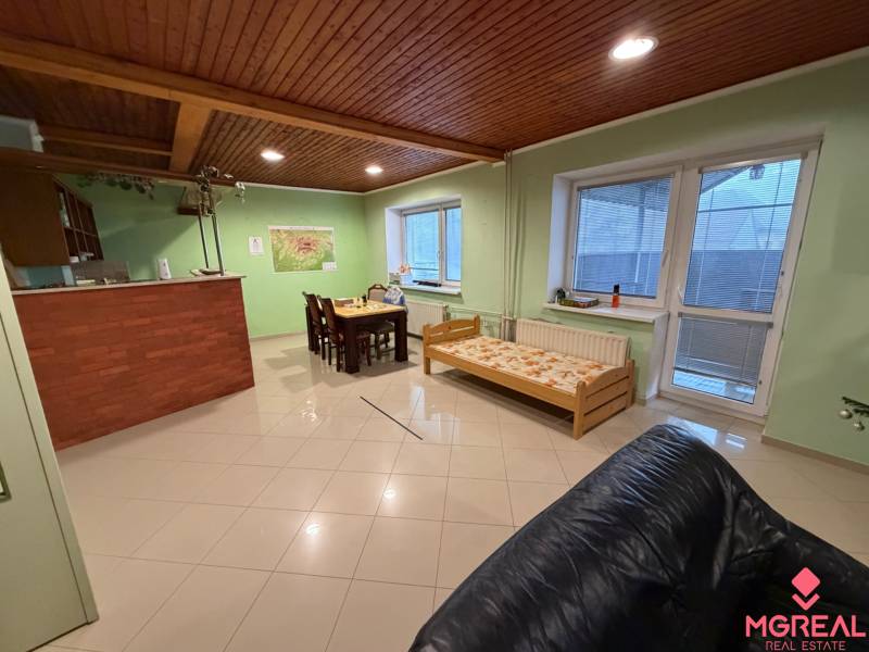 Veľký rodinný dom Podhradie  - Obývací priestor s jedálenským stolom, dreveným stropom a posteľou v Rodinnom dome.