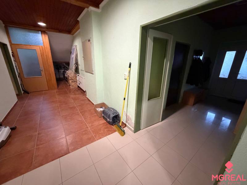 Veľký rodinný dom Podhradie  - Chodba rodinného domu s dlažbou, dverami a vešiakmi na oblečenie.
