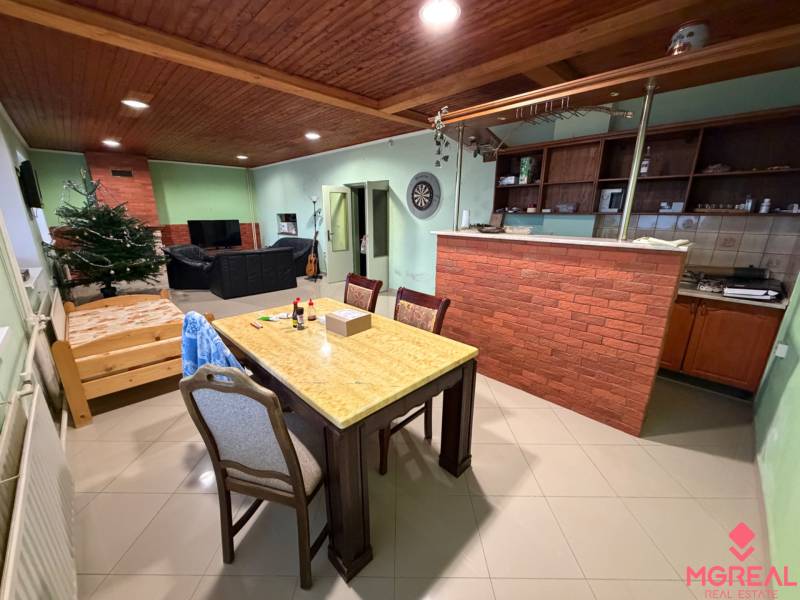 Veľký rodinný dom Podhradie  - Obývačka rodinného domu s tehlovým pultom, jedálňou, pohovkou a podlahou s dreveným dekorom.