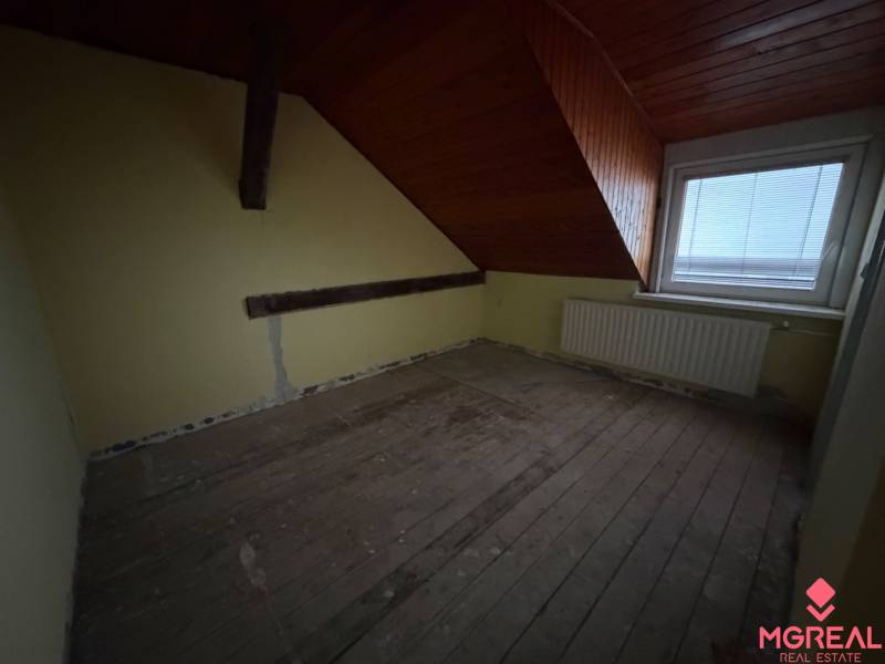 Veľký rodinný dom Podhradie  - Podkrovná izba v rodinnom dome s trámami a strešným oknom.