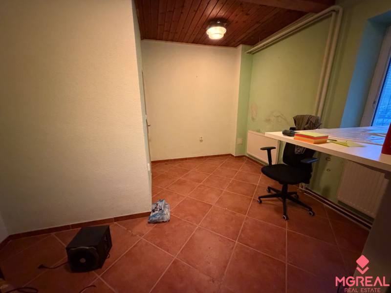 Veľký rodinný dom Podhradie  - Izba v rodinnom dome s kachličkovou podlahou, stolom, stoličkou a stropným svietidlom.