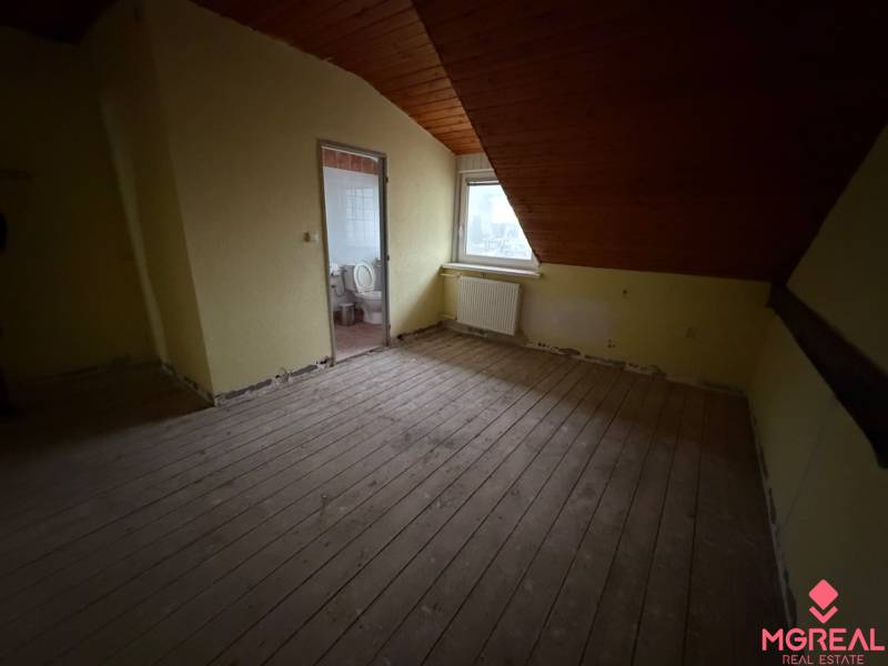 Veľký rodinný dom Podhradie  - Izba v podkroví rodinného domu s dreveným stropom a výhľadom na mesto.