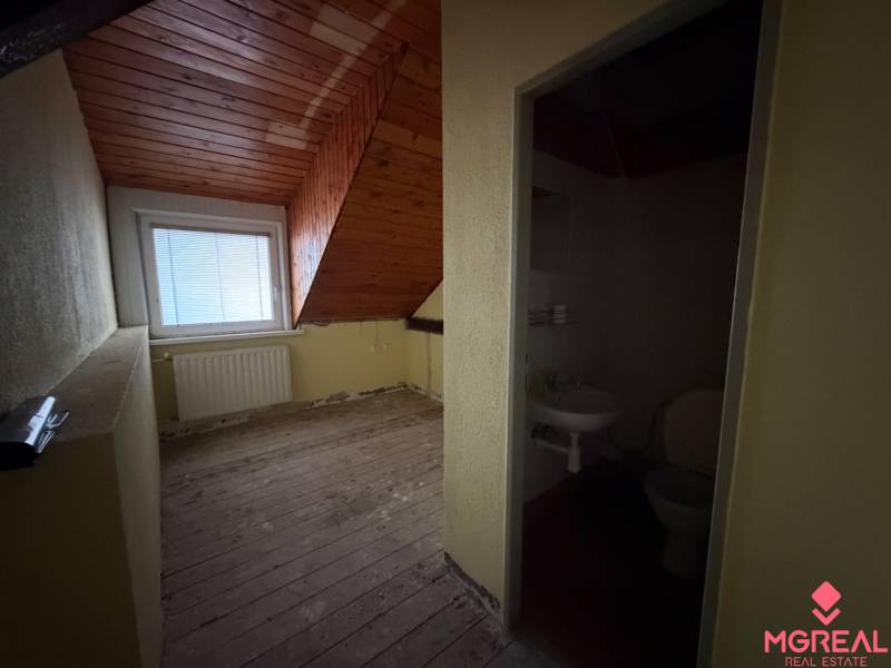 Veľký rodinný dom Podhradie  - Podkrovná izba s dreveným stropom a susediacou kúpeľňou v rodinnom dome.