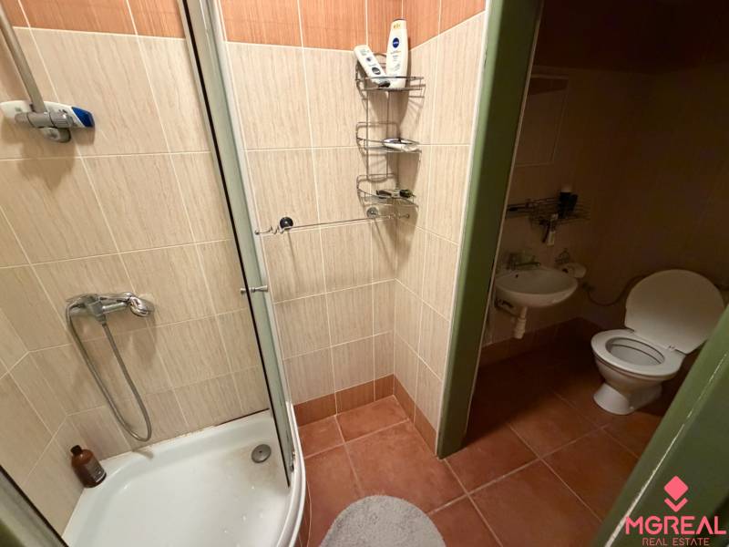Veľký rodinný dom Podhradie  - Kúpeľňa v rodinnom dome s dlažbou, sprchou a WC bez okna.