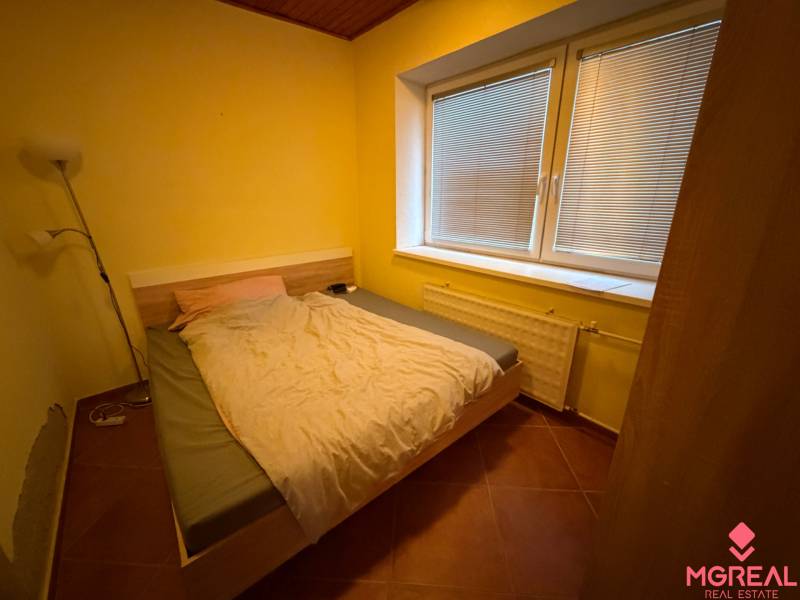 Veľký rodinný dom Podhradie  - Spálňa v rodinnom dome s manželskou posteľou, lampou a veľkým oknom s žalúziami.