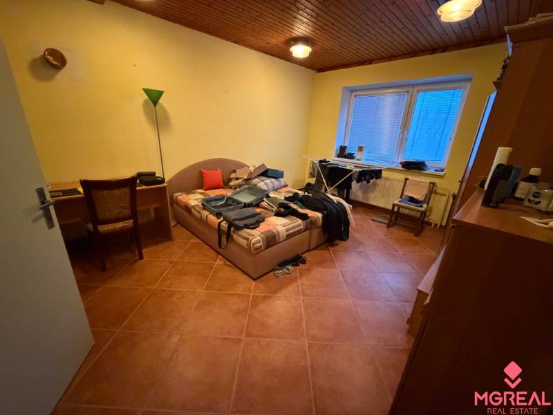 Veľký rodinný dom Podhradie  - Spálňa v rodinnom dome s posteľou, stolom, stoličkou a podlahou s dreveným dekorom.