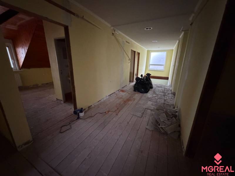 Veľký rodinný dom Podhradie  - Chodba v rodinnom dome s podlahou s dreveným dekorom, pripravená na renováciu.