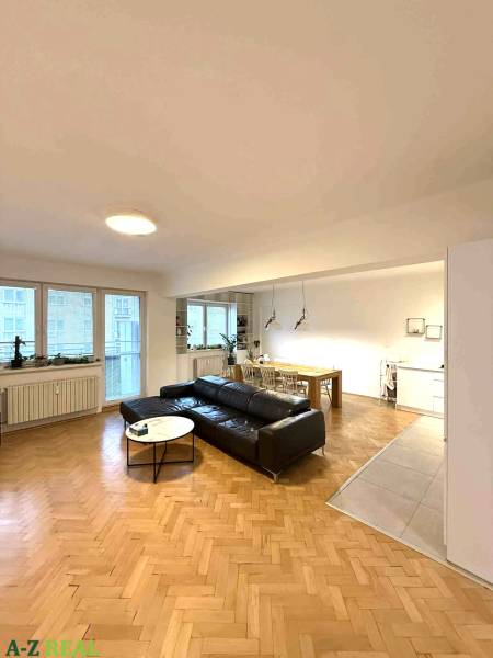 Prenájom 4 izb. bytu, Blumentálska ulica, Staré Mesto - Obývacia izba v 4-izbovom byte s podlahou s dreveným dekorom a čiernym gaučom.