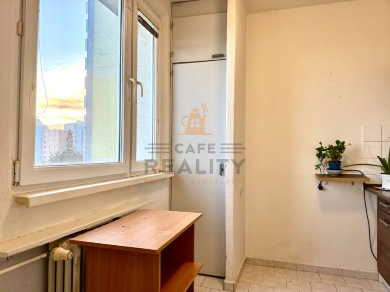 REZERVOVANÉ Na predaj 1 izbový byt, Bratislava, Dúbravka, Drobného - Interiér 1-izbového bytu s oknom, stolíkom, rastlinami na poličke a radiátorom pod oknom.