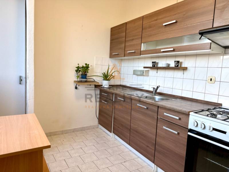 REZERVOVANÉ Na predaj 1 izbový byt, Bratislava, Dúbravka, Drobného - Kuchyňa s linkou a sporákom v 1-izbovom byte, svetlé dlaždice, drevený dekor.