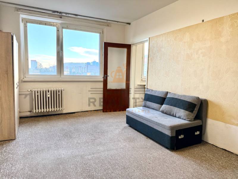 REZERVOVANÉ Na predaj 1 izbový byt, Bratislava, Dúbravka, Drobného - Obývacia izba v 1-izbovom byte s pohovkou a veľkým oknom so svetlom.