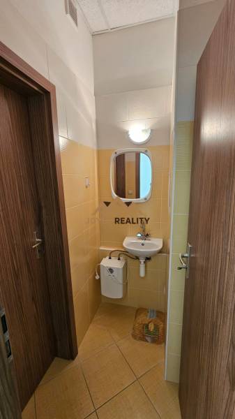 Na prenájom: Nebytový-obchodný priestor – Budovateľská ulica, Šaľa - Kúpeľňa v obchodných priestoroch s umývadlom a zrkadlom, obložená svetlými kachličkami.