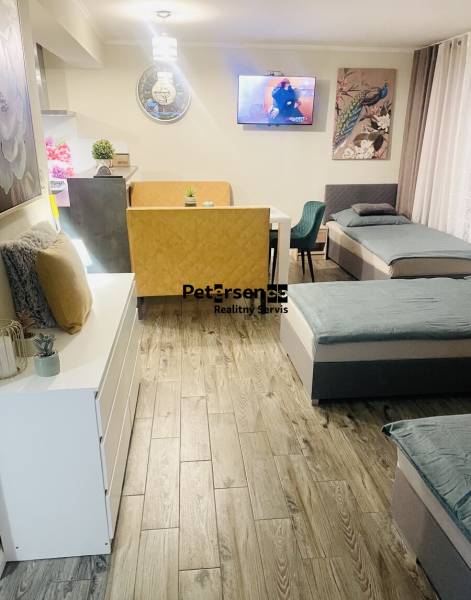 KRÁSNY DVOJPODLAŽNÝ RODINNÝ DOM NA PRENÁJOM - Obývací priestor v rodinnom dome so sedačkou, kreslom, televízorom a podlahou s dreveným dekorom.