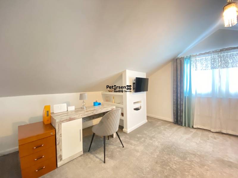 KRÁSNY DVOJPODLAŽNÝ RODINNÝ DOM NA PRENÁJOM - Izba v rodinnom dome s pracovným stolom, televízorom a svetlým kobercom.