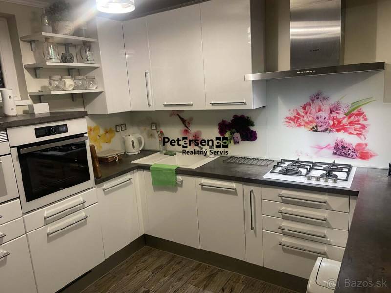 KRÁSNY DVOJPODLAŽNÝ RODINNÝ DOM NA PRENÁJOM - Kuchyňa v Rodinnom dome s bielymi skrinkami, dekoratívnym obkladom a podlahou s dreveným dekorom.