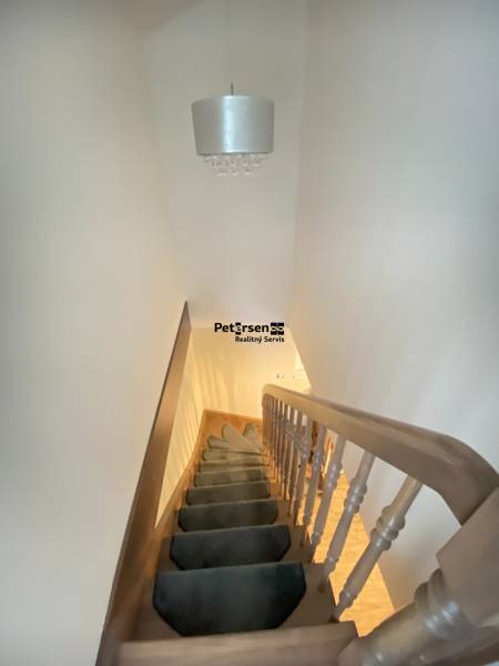 KRÁSNY DVOJPODLAŽNÝ RODINNÝ DOM NA PRENÁJOM - Schodisko s kobercom vedie nahor, nad ním visí svietidlo v rodinnom dome.