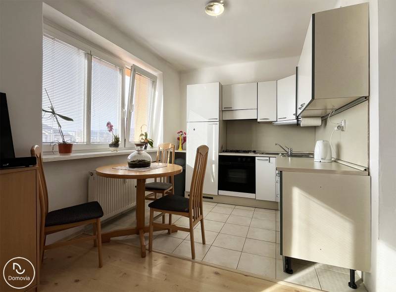 Exkluzívne | Na prenájom priestranný 1i byt Ružinove - Kuchyňa v 1-izbovom byte s okrúhlym stolom a podlahou s dreveným dekorom.