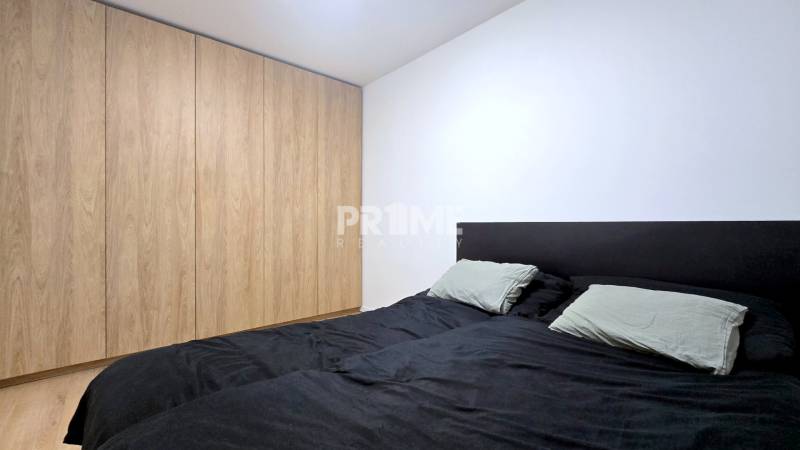 Moderný, rekonštruovaný 3i byt, pivnica, Jašíkova ul., Ružinov - Pošeň - Spálňa v 3-izbovom byte s bielymi stenami a vstavanou skriňou s dreveným dekorom.