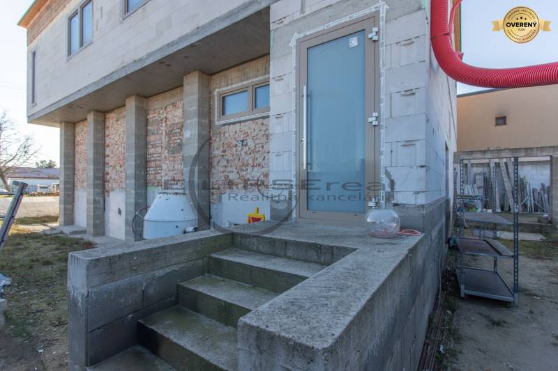 NA PREDAJ polyfunkčná budova v centre obce Veľké Leváre - Budova vo Veľkých Levároch s nedokončenou fasádou a schodmi na betónovom základe.