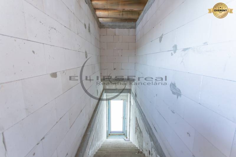 NA PREDAJ polyfunkčná budova v centre obce Veľké Leváre - Pohľad na schodisko v budove s betónovými stenami a oknom na konci.