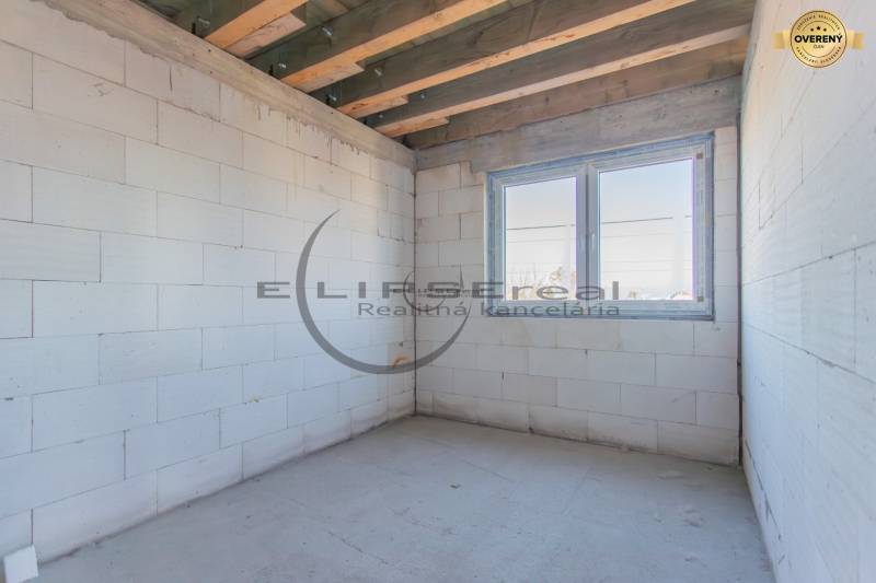 NA PREDAJ polyfunkčná budova v centre obce Veľké Leváre - Prázdna miestnosť s bielymi stenami, dreveným stropom a veľkým oknom v budove.
