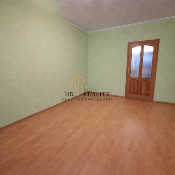 Predaj 2 izbový byt s dvoma balkónmi v Nižnej. - Prázdny izba s podlahou s dreveným dekorom a zelenými stenami v 2-izbovom byte.