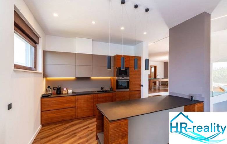 Novalja – luxusná vila s bazénom, jacuzzi a výhľadom na more - Kuchyňa vo Vile s podlahou s dreveným dekorom a štýlovým osvetlením.