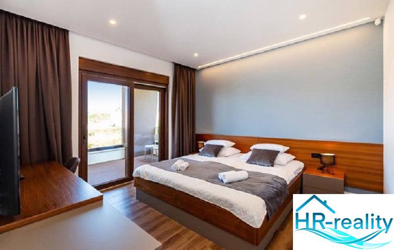 Novalja – luxusná vila s bazénom, jacuzzi a výhľadom na more - Izba s posteľou vily, podlaha s dreveným dekorom, balkón s výhľadom.