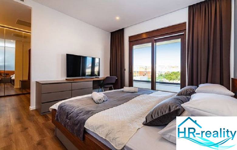 Novalja – luxusná vila s bazénom, jacuzzi a výhľadom na more - Štýlová spálňa s veľkou posteľou, televízorom a podlahou s dreveným dekorom vo Vile.