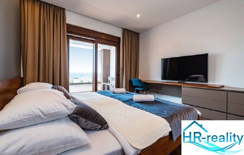 Novalja – luxusná vila s bazénom, jacuzzi a výhľadom na more - Spálňa vo Vile s podlahou s dreveným dekorom, posteľou, TV a výhľadom na terasu.