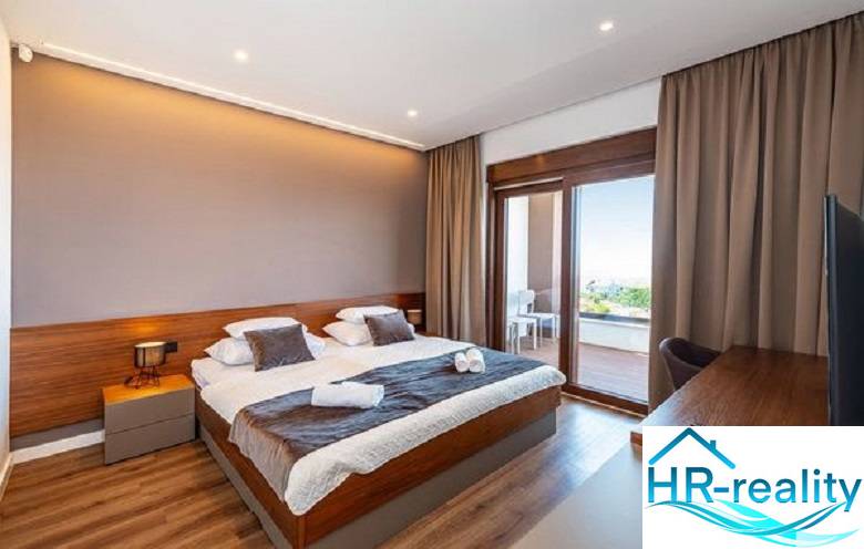 Novalja – luxusná vila s bazénom, jacuzzi a výhľadom na more - Luxusná spálňa vo vile s balkónom, podlaha s dreveným dekorom, veľké okná.