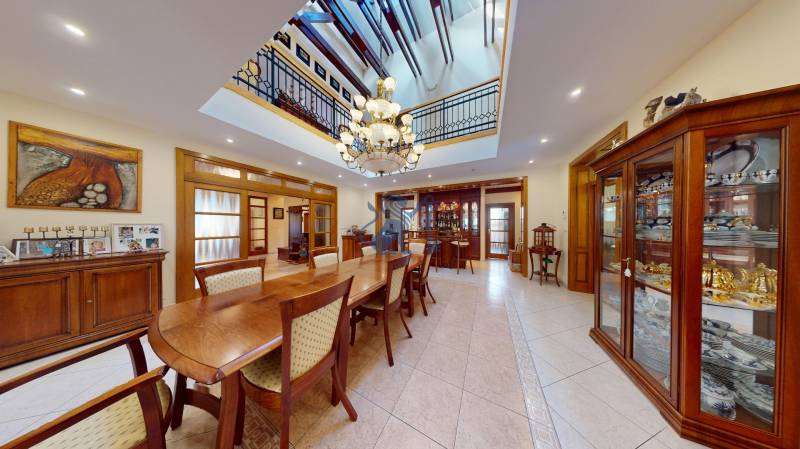 Veľkometrážny dom s wellness, bazénom a investičným potenciálom - Jedáleň v rodinnom dome s veľkým dreveným stolom, lustrom a vitrínami s porcelánom.