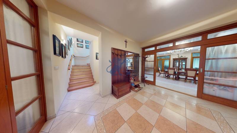 Veľkometrážny dom s wellness, bazénom a investičným potenciálom - V rodinnom dome je vstupná hala s dlažbou, schodiskom a jedálňou za presklenými dverami.