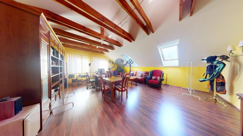 Veľkometrážny dom s wellness, bazénom a investičným potenciálom - Podkrovná izba v Rodinnom dome s podlahou s dreveným dekorom, sedacou súpravou a stolom.