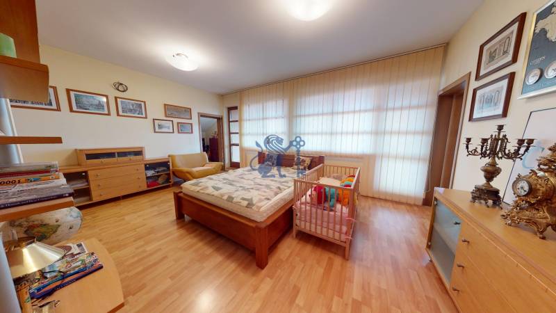 Veľkometrážny dom s wellness, bazénom a investičným potenciálom - Spálňa v rodinnom dome s dreveným dekorom podlahy, detská postieľka a dekorácie.