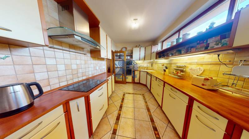 Veľkometrážny dom s wellness, bazénom a investičným potenciálom - Kuchyňa v rodinnom dome s drevenými skrinkami a dlažbou na podlahe.